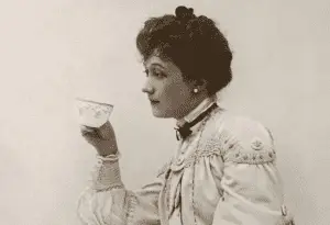 Black and white photo of American actress and singer Lillian Russell, drinking tea.