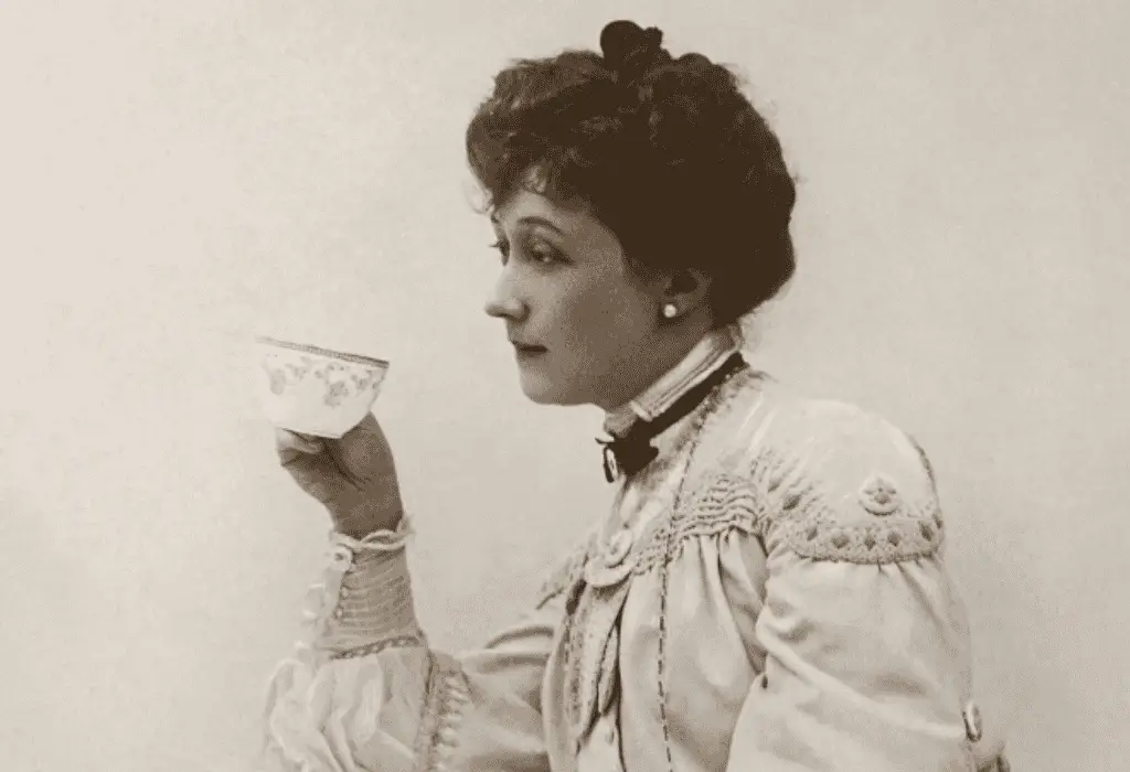 Black and white photo of American actress and singer Lillian Russell, drinking tea.