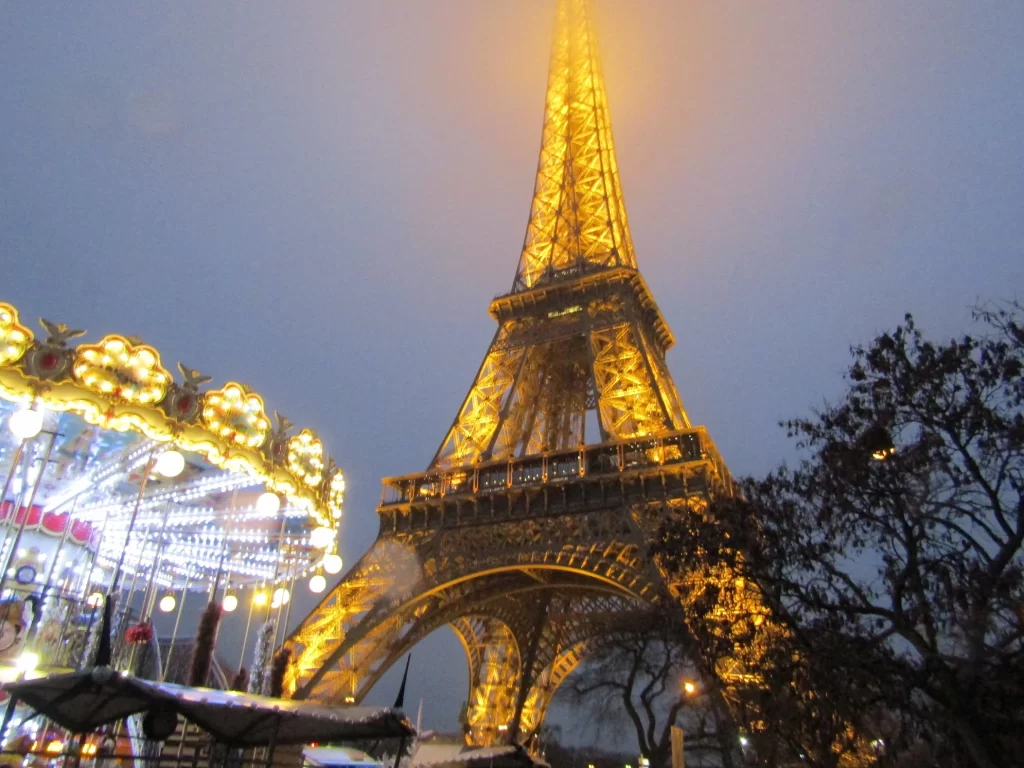 Eiffel Tower lit up at night next to an illuminated carousel